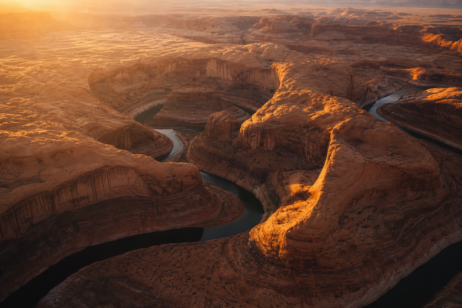a desert canyon at golden hour, sweeping sandstone curves, deep shadows, aerial photograph