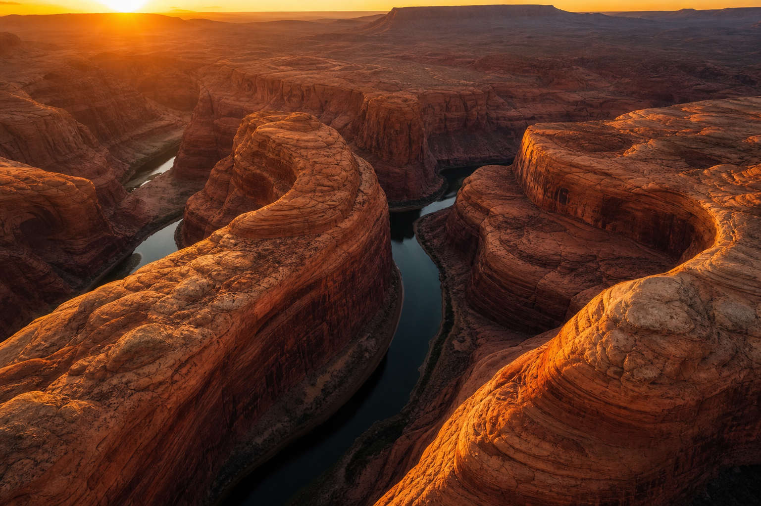 a desert canyon at golden hour, sweeping sandstone curves, deep shadows, aerial photograph