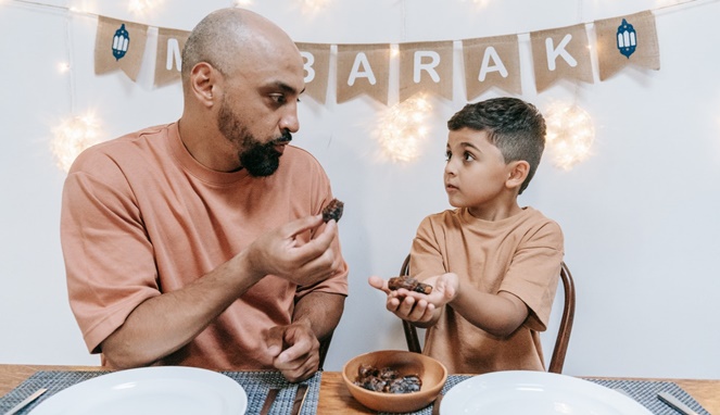 Ilustrasi ayah dan anak sedang makan kurma. [Sumber Gambar]