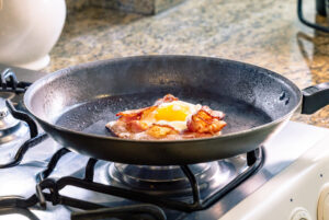 A black cast iron skillet for frying egg with bacon