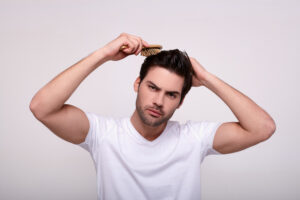 Man touching hair with a brush wondering how to pick the best pomade