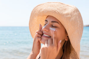 smiling woman hat is applying sunscreen her face indian style
