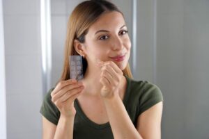 A girl applying acne treatment pimple patch in the bathroom at home