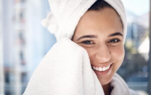 A woman compressing her face with a clean towel and water