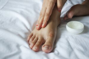 A person applying petroleum jelly on foot