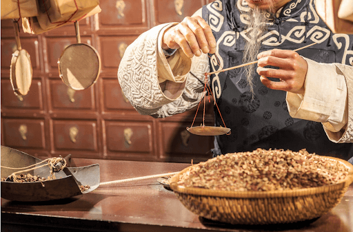 Chinese man weighing TCM herbs using a scale