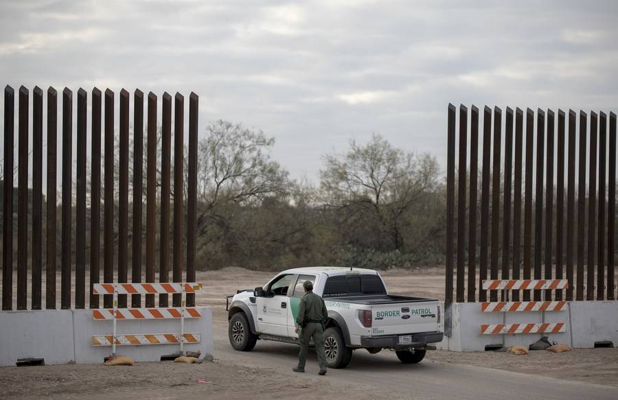 A U.S. Border Patrol agent walks to his vehicle while patrolling near a newly-built section of the border wall between Mexico and the United States near Eagle Pass, Texas, the United States