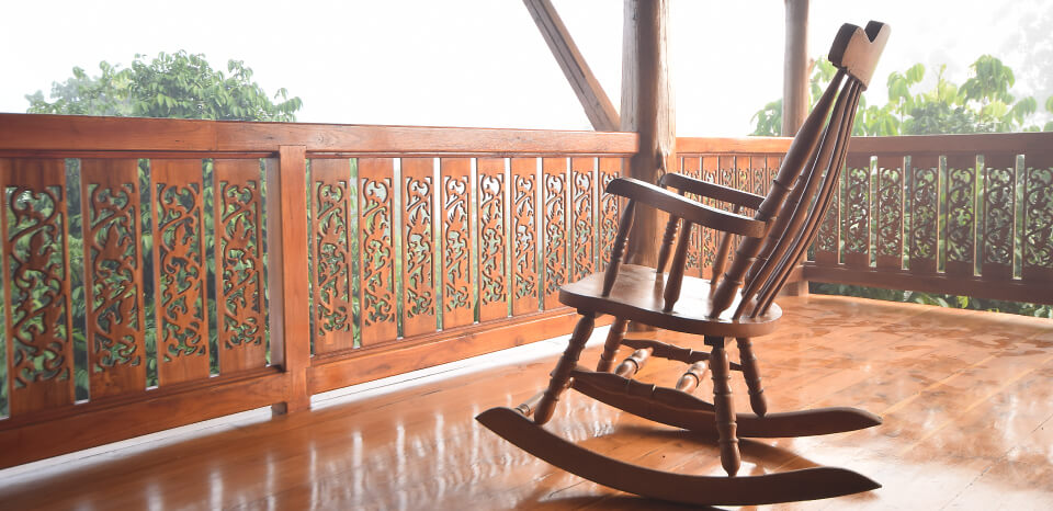 A wooden balcony with a wooden chair coated with sayerlack wood coating
