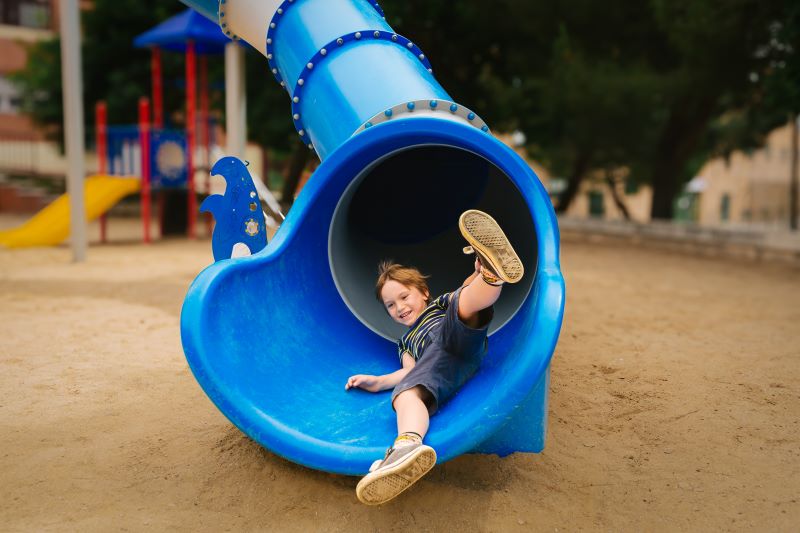 Young boy emerges from playground slide