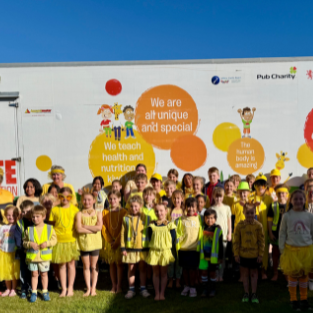 Children dressed in yellow outside a mobile classroom