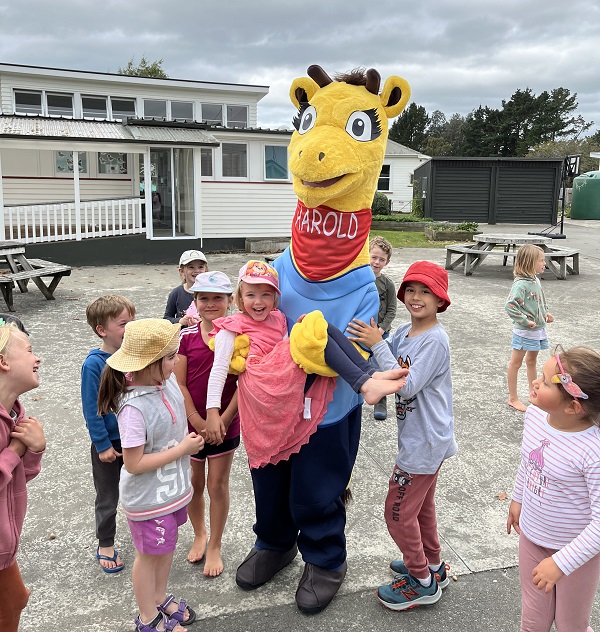 Students and Harold the Giraffe in the playground