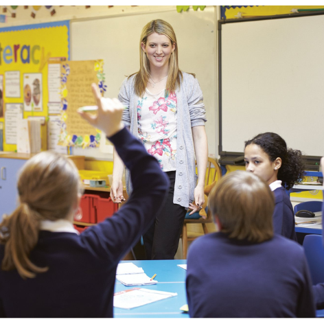 Students with their hands up in front of teacher