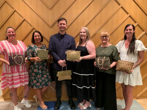 Six educators holding kete
