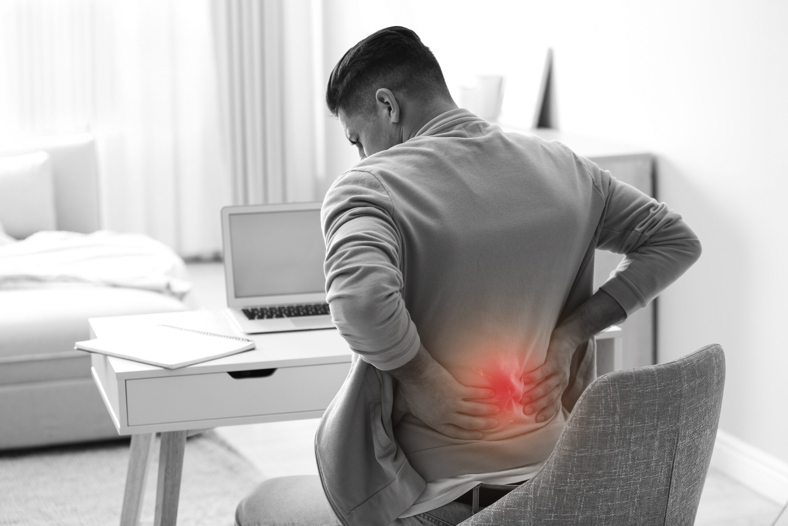 Man suffering from back pain at workplace. Bad posture problem