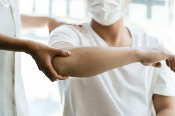 Professional Male Physical Therapist Helping his male Patient in Exercising the Injured Shoulder.