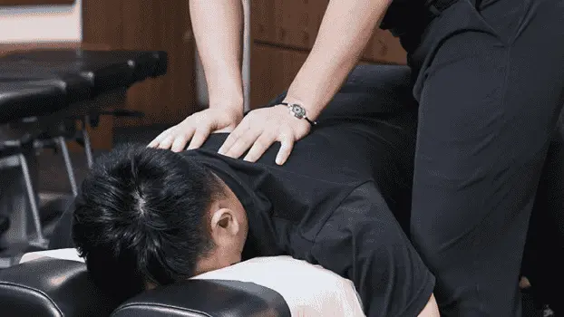 a man dressed in black receiving chiropractic treatment