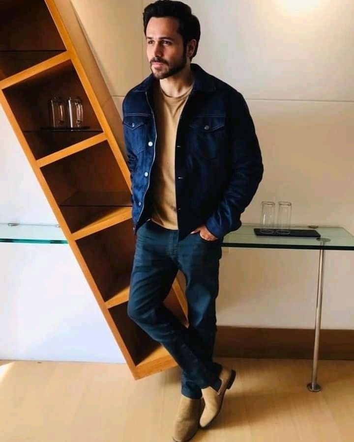 This may contain_ a man standing in front of a glass table next to a shelf with wine glasses on it This may contain_ a man standing in front of a glass table next to a shelf with wine glasses on it
