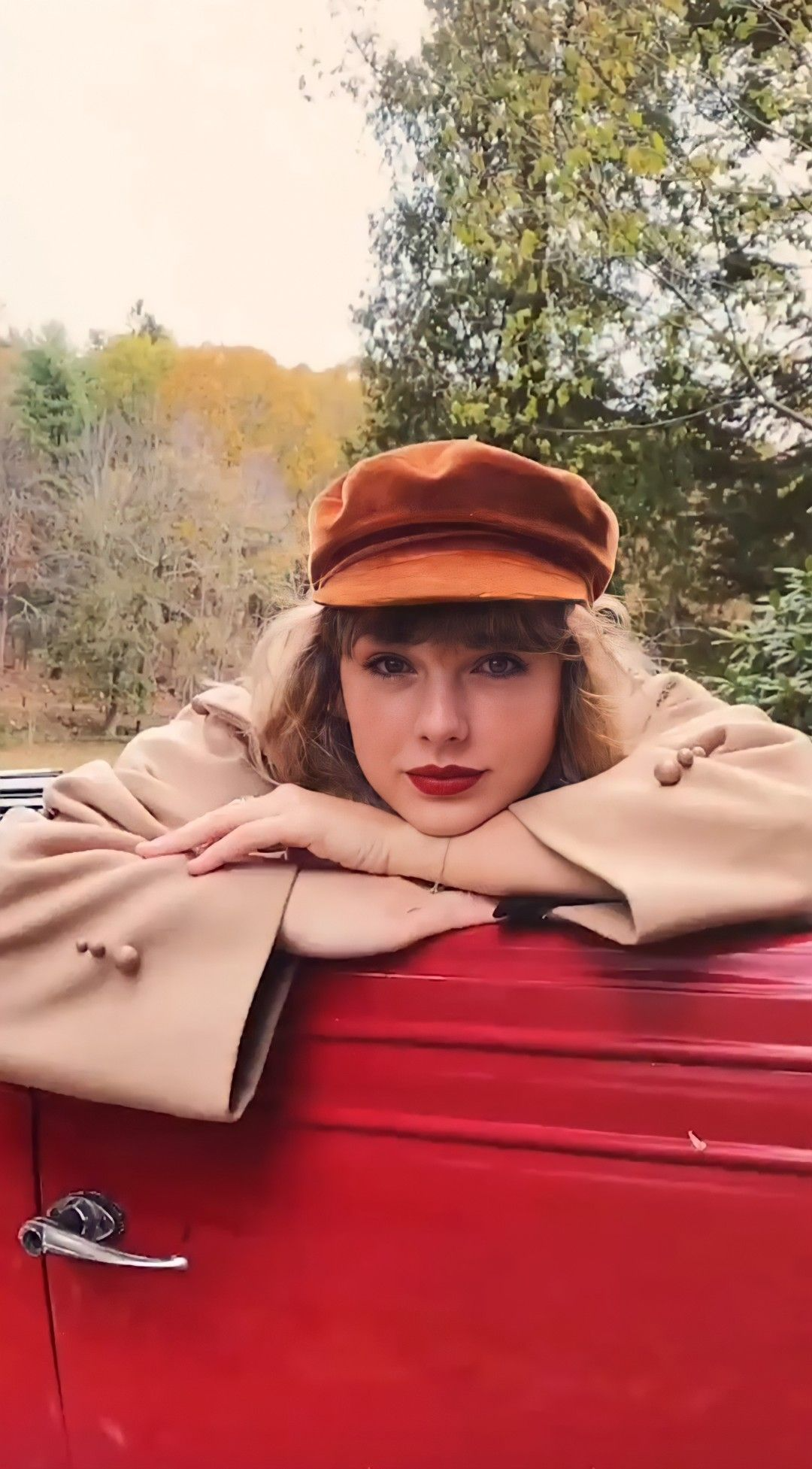This may contain_ a woman leaning on top of a red car