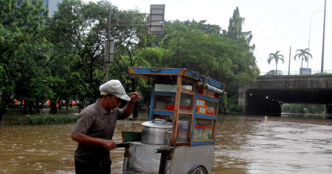 Warga melintas saat banjir yang merendam kawasan Cawang, Jakarta, Rabu (1/1). Banjir tersebut membuat lalu lintas kawasan Cawang lumpuh. Foto : Ricardo