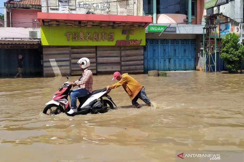 Pengendara motor melintasi genangan banjir di Jalan Raya Dayeuhkolot, Kabupaten Bandung. Foto: ANTARA/Bagus Ahmad Rizaldi