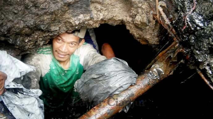 TAK TAKUT KOTOR DAN BAU: Maman, seorang warga Desa Cipanas, nekat masuk ke dalam lubang gorong-gorong untuk mengangkat sampah yang menyebabkan banjir. FOTO : DADAN/RADAR CIANJUR