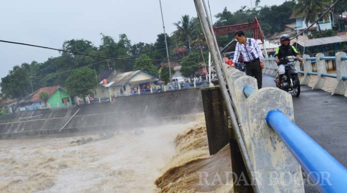 HENDI novian/RADAR bogor HUJAN MERATA: Warga melintas dan melihat kondisi bendung air Katulampa yang masih berstatus aman. 