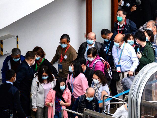 BEBAS VIRUS KORONA: Penumpang kapal pesiar World Dream antre turun di Kai Tak Cruise Terminal, Hongkong, Minggu (9/2). Sebanyak 3.600 penumpang dan kru diperbolahkan keluar setelah dikarantina lima hari. (Philip FONG/AFP)