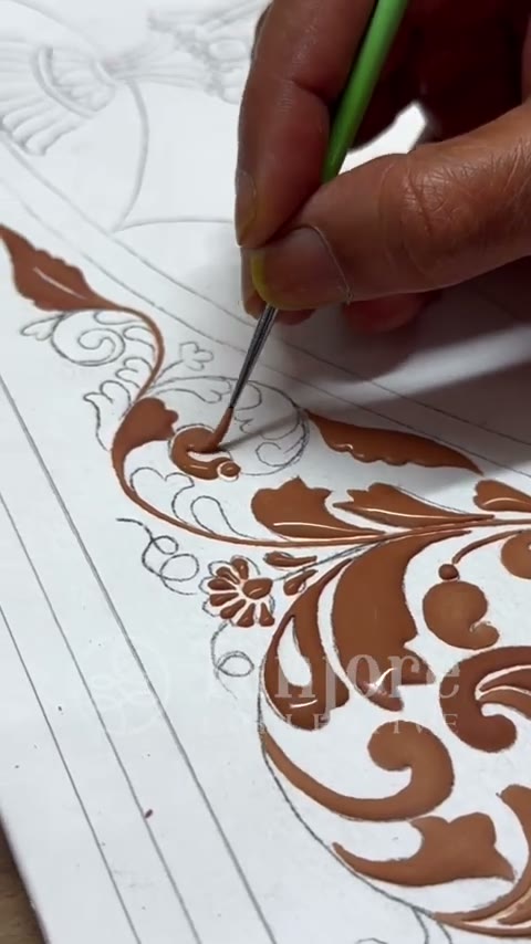 An artist drawing the fine outline of a Tanjore design by hand