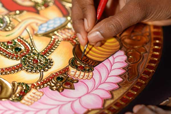 An artist painting a Tanjore Lakshmi with a fine brush