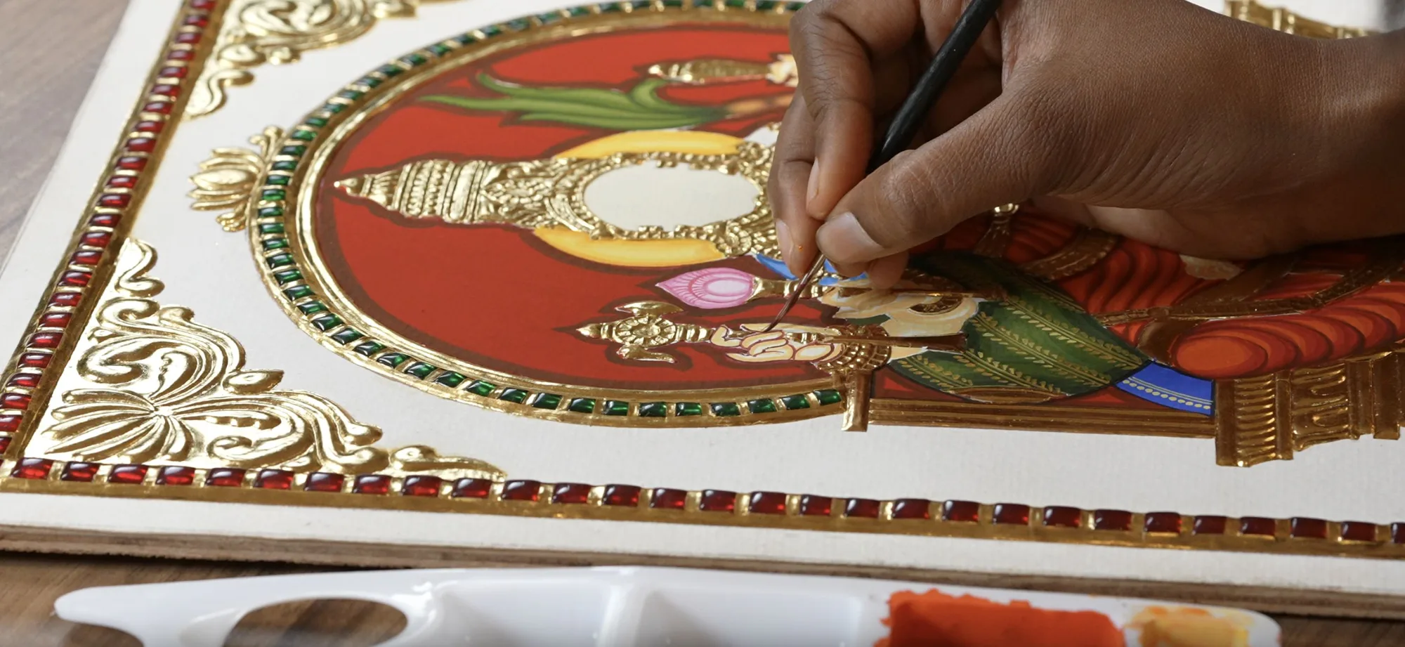 An artist adding fine gold detailing to a Tanjore painting