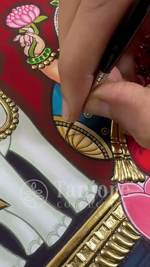 An artist hand painting the ornament detail of a Tanjore painting