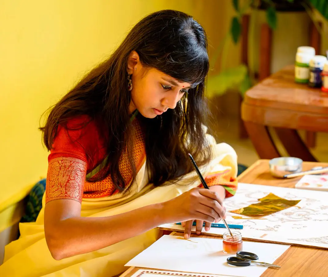 A Tanjore artist working on a painting at a table in the studio