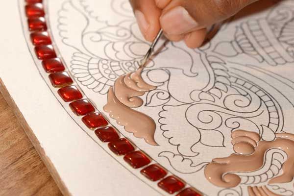 Raised embossing relief being worked along the border of a Tanjore painting sketch