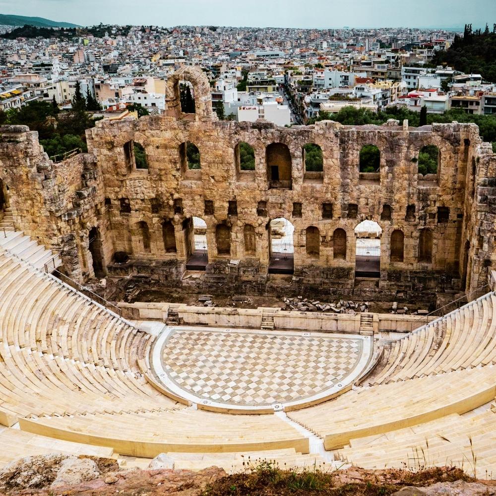 An ancient stone amphitheatre overlooking a city in Greece