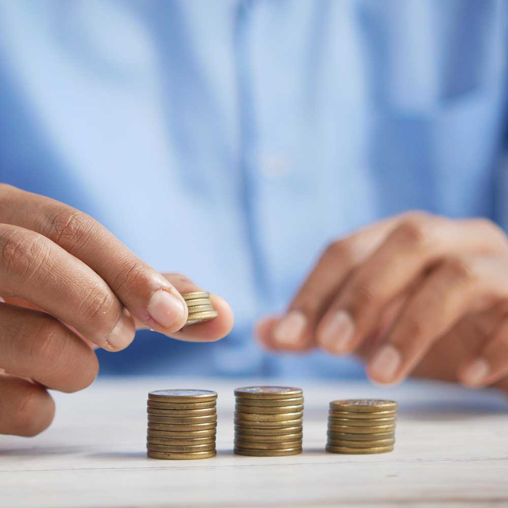 A man stacking coins and calculating expenses