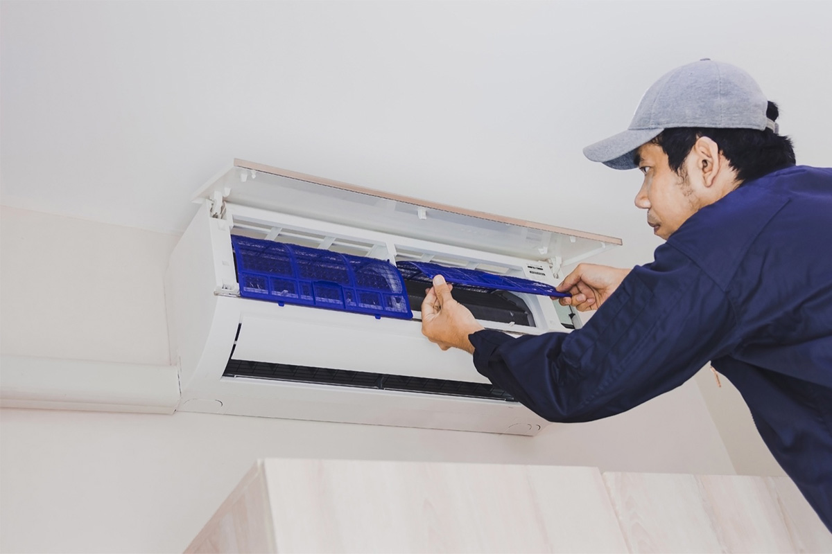 Technician servicing an indoor wall-mounted aircon unit