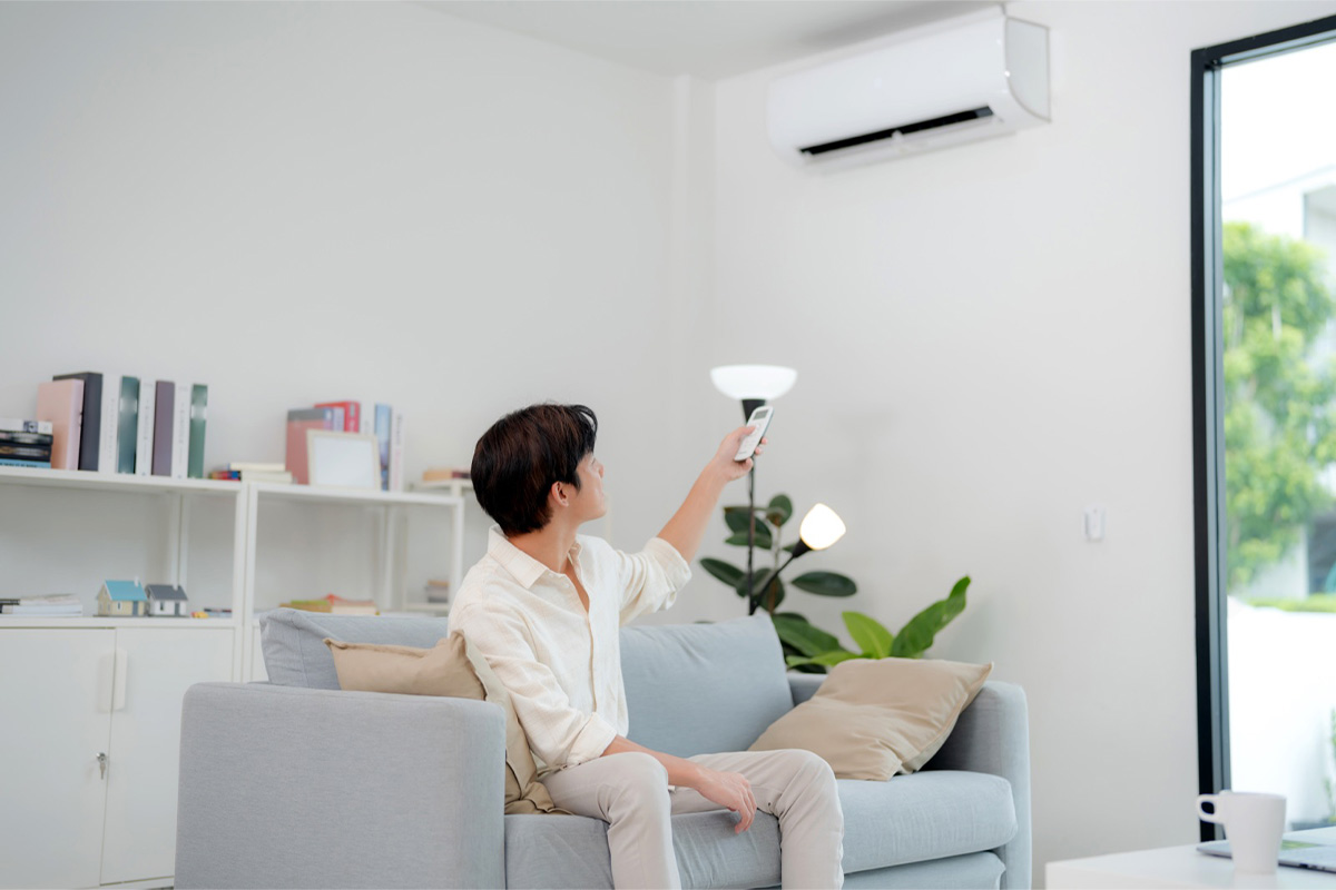 Homeowner using a remote to control wall-mounted aircon