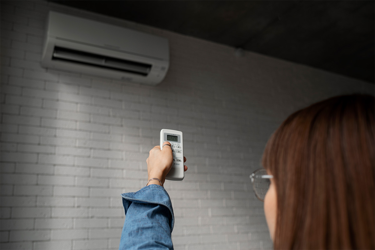 Homeowner using a remote to control a wall-mounted aircon unit