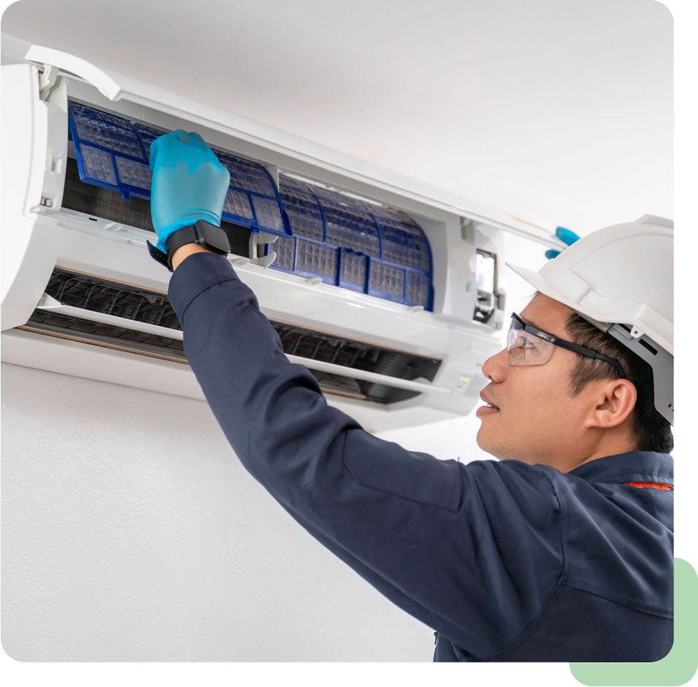 Technician in safety gear servicing a wall-mounted aircon unit