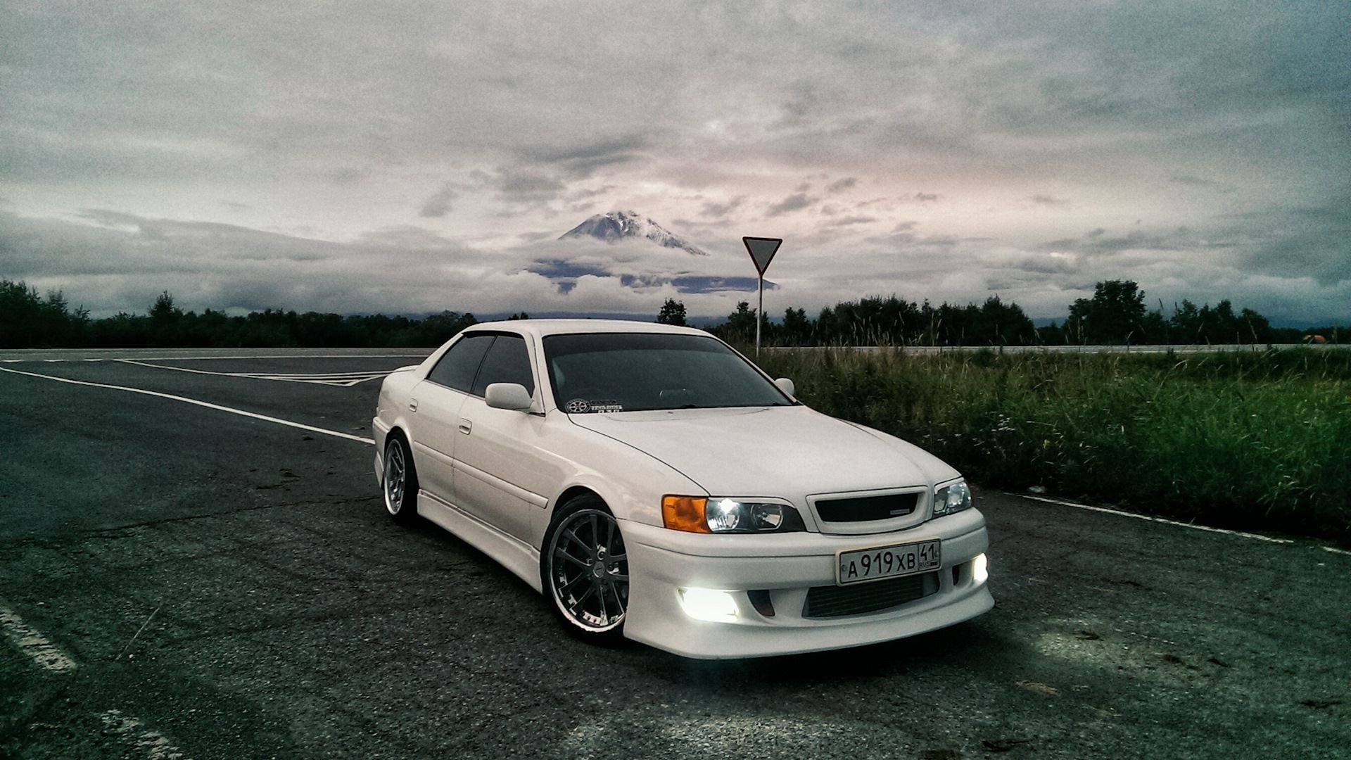 Front view of a white Toyota Chaser with a scenic background.