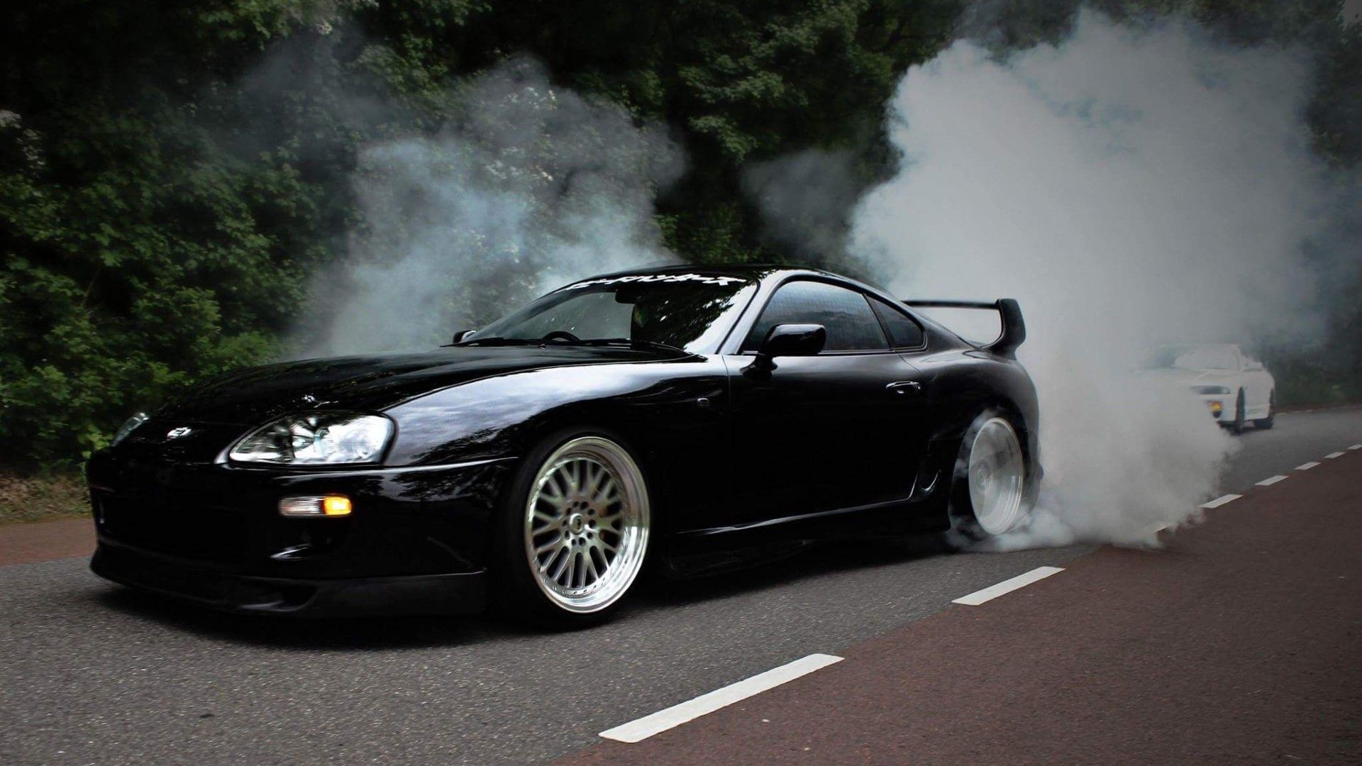 Front view of a black Toyota Supra performing a burnout.