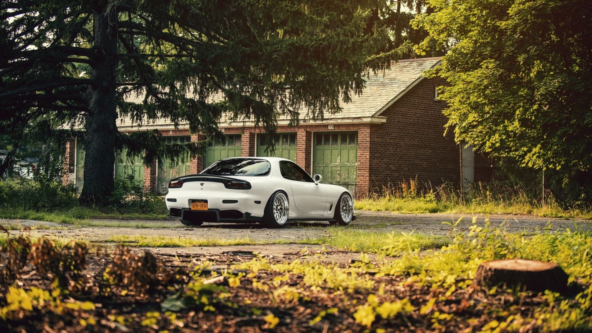 Rear view of a white Mazda RX-7 parked in a scenic area.