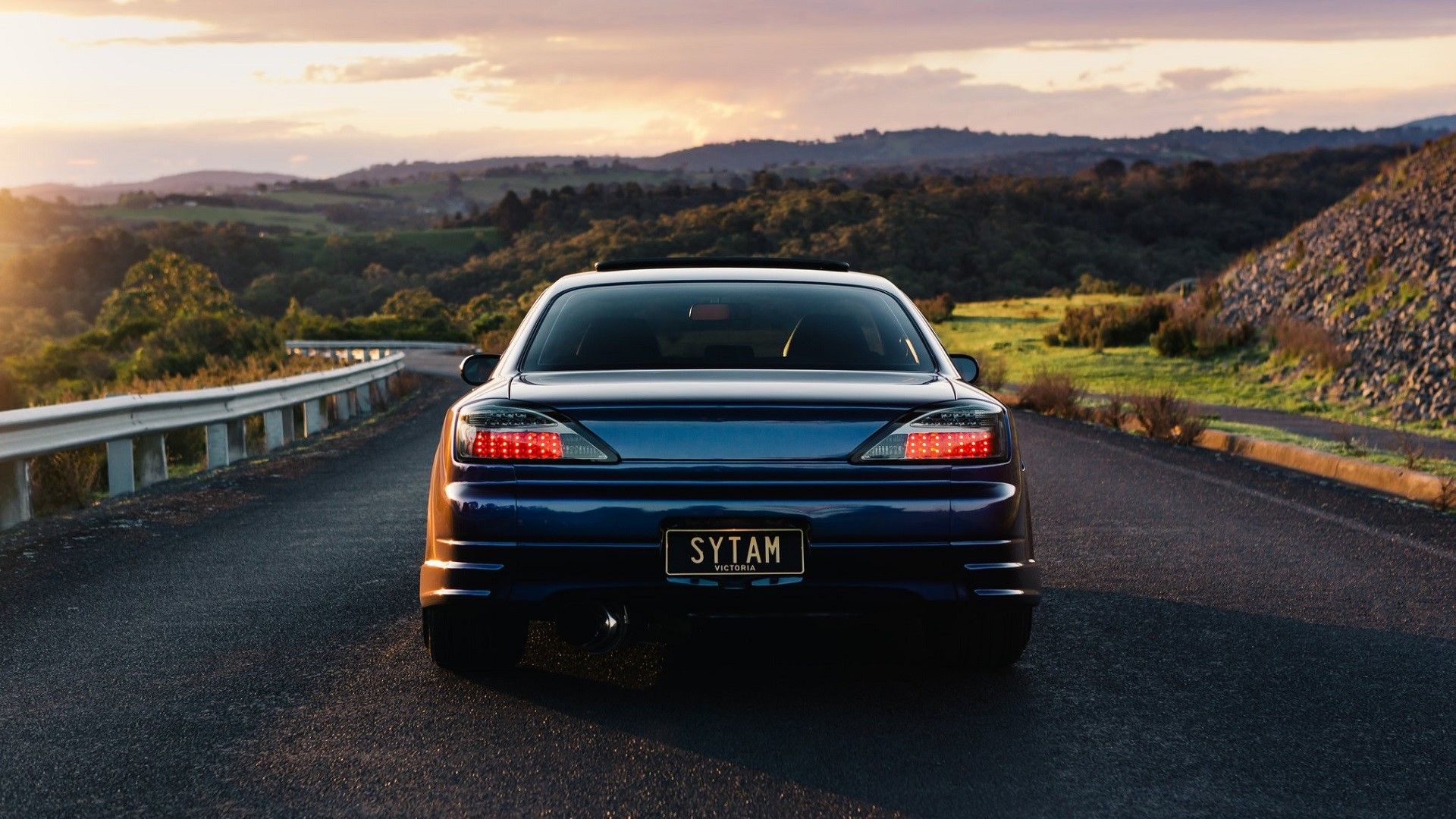 Rear view of a blue Nissan Silvia S15 in a scenic area.