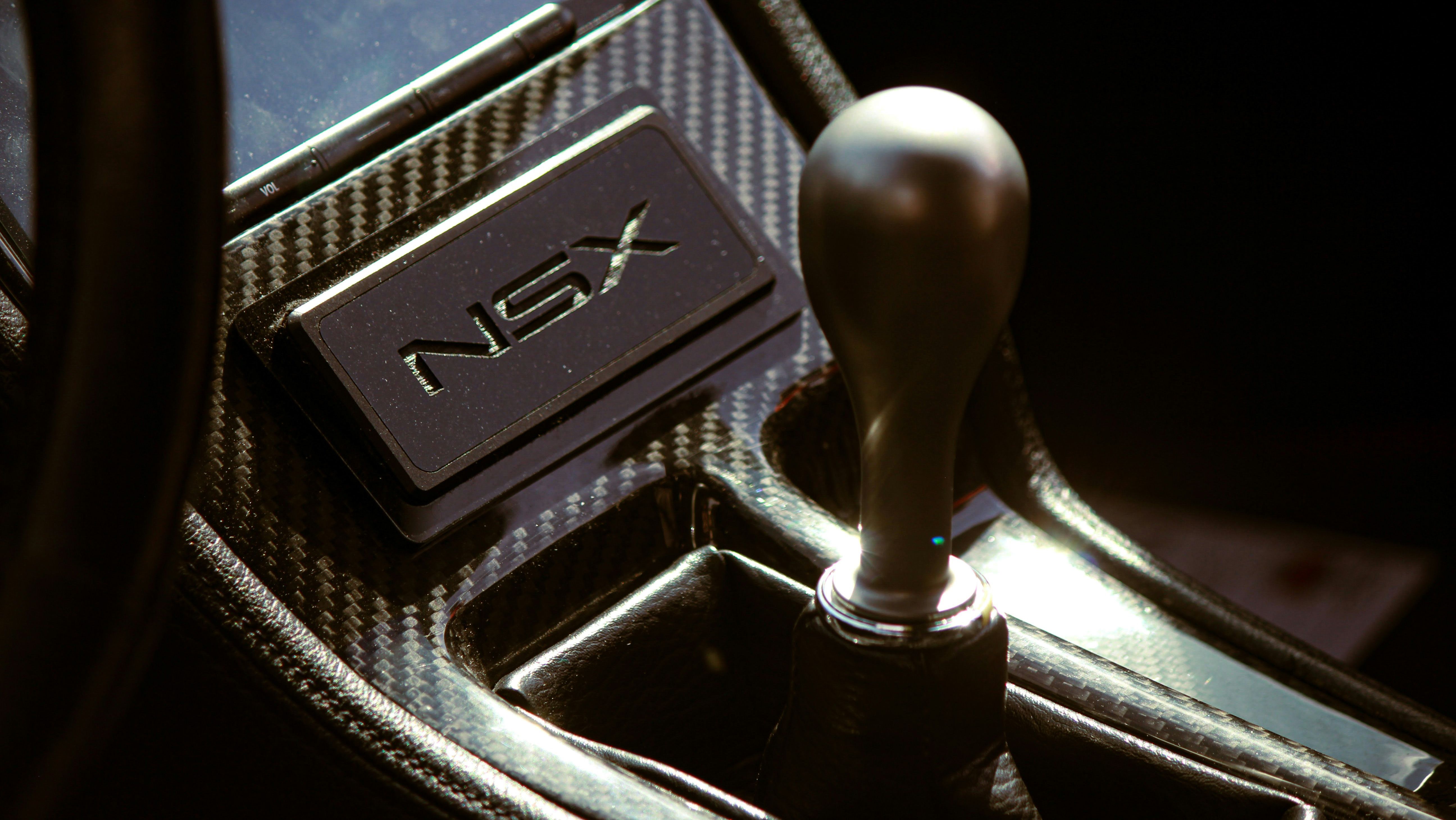 Close-up of a Honda NSX interior featuring a carbon fiber trim and sleek manual shift knob, highlighting the JDM performance aesthetic.