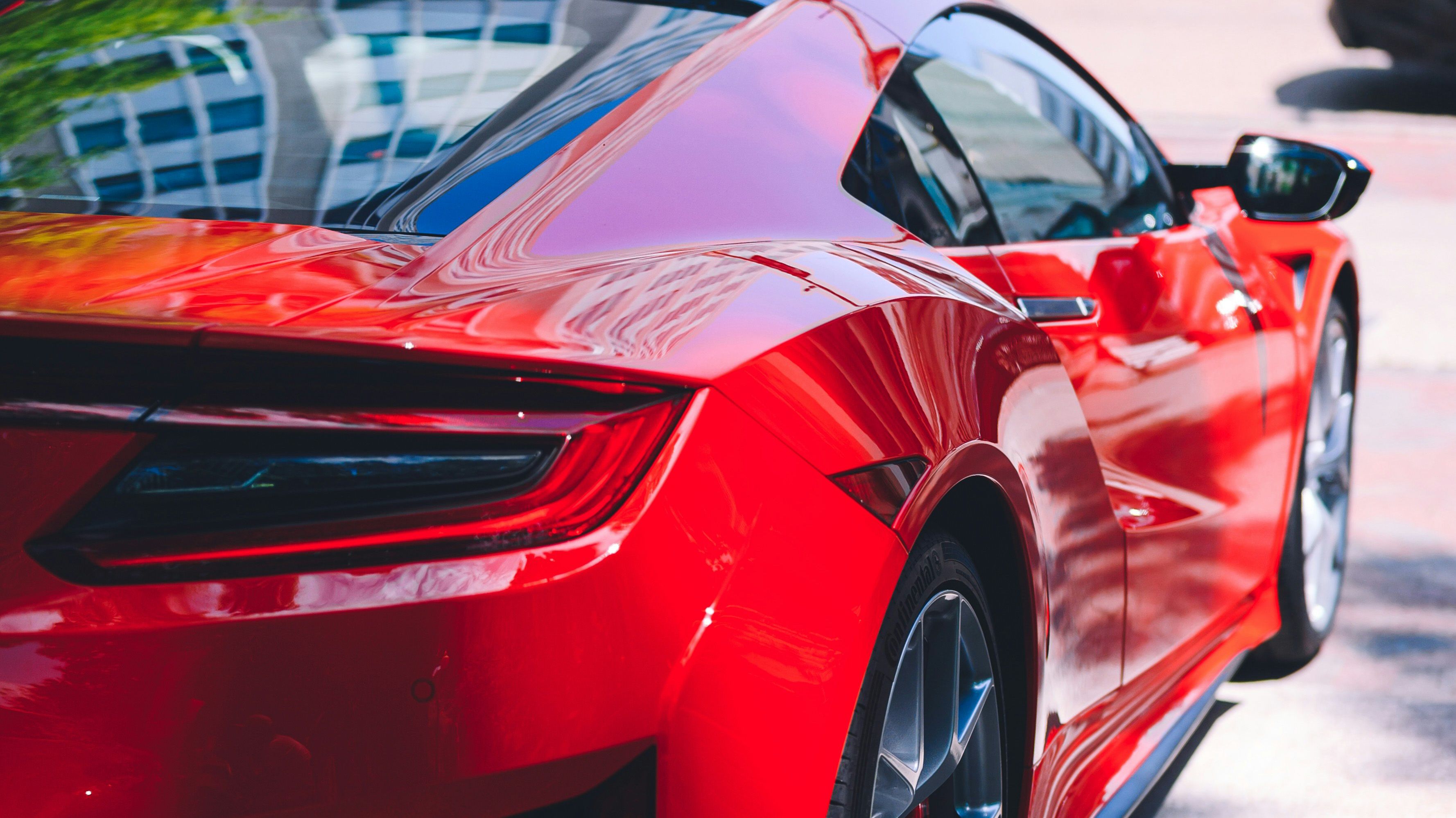 Red Honda NSX with sleek curves, JDM styling, and sharp taillights reflecting urban vibes, emphasizing its modern performance design.