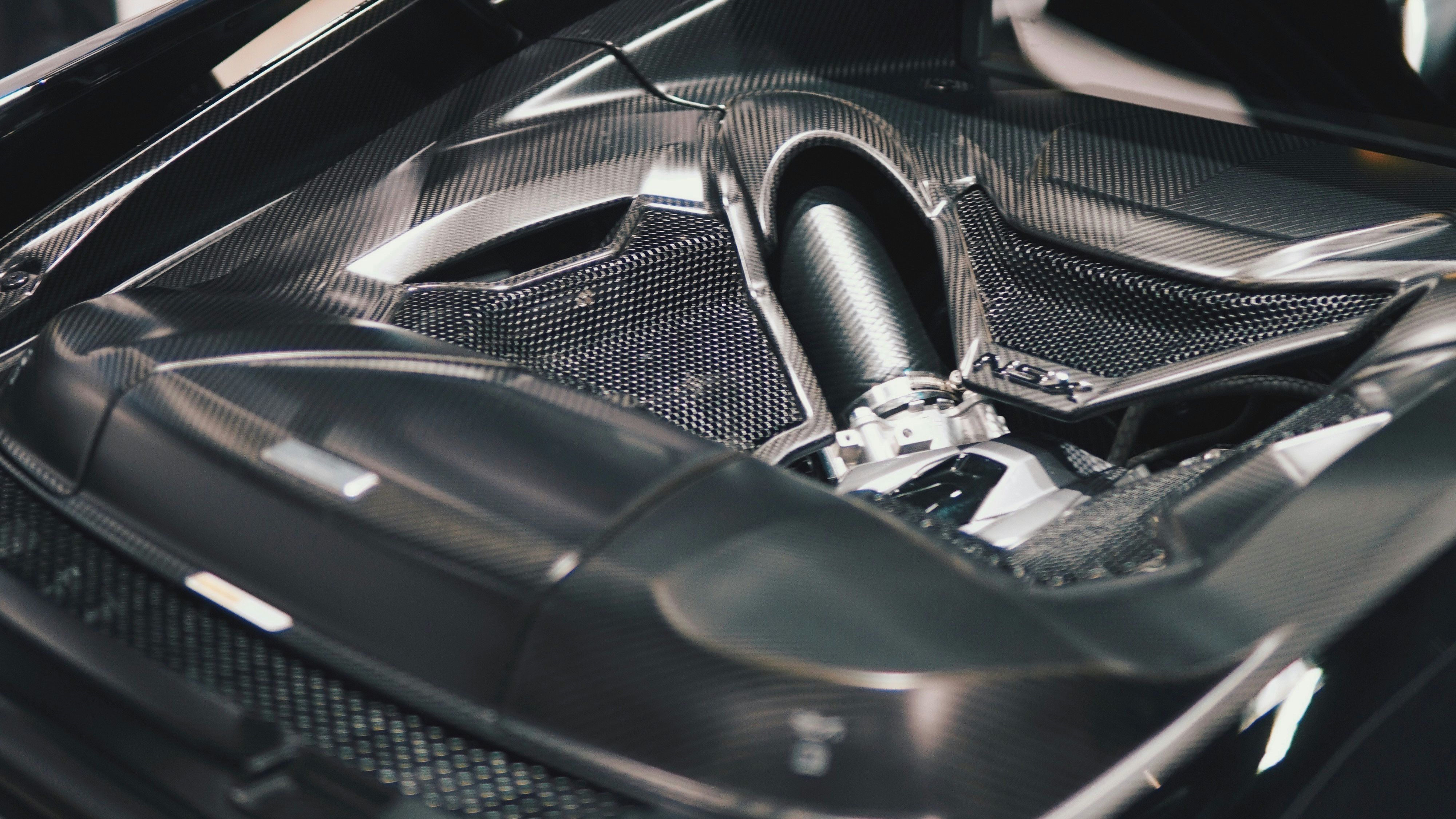 Close-up view of an NSX engine bay featuring exposed carbon fiber components. The performance-focused design screams JDM power and precision engineering.
