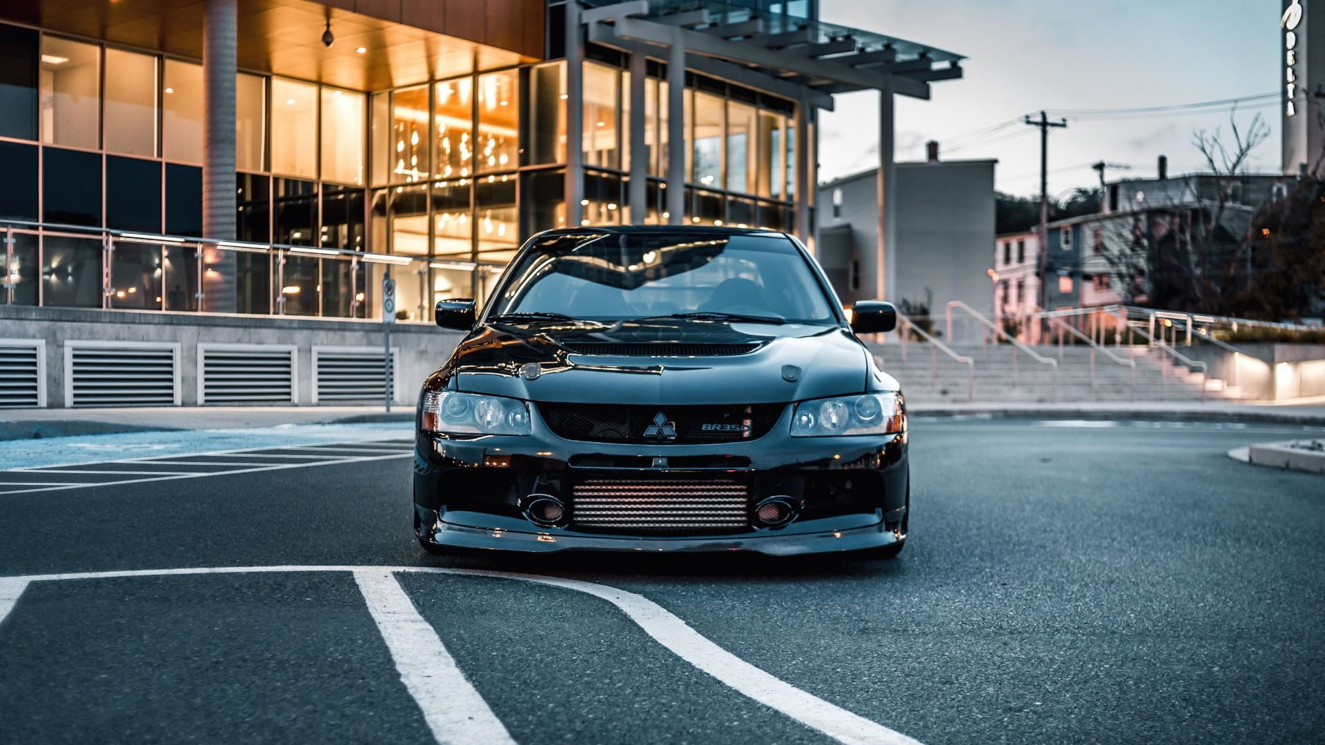 Front view of a black Mitsubishi Lancer Evolution parked in a car park at dusk.