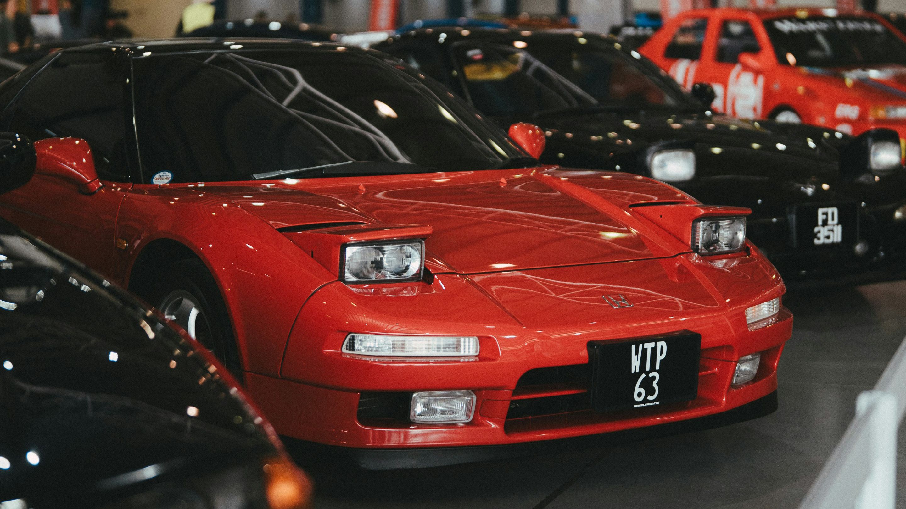 A classic red Honda NSX showcased indoors, reflecting iconic JDM aesthetics. This legendary mid-engine sports car is a symbol of 90s Japanese performance, capturing attention with its pop-up headlights and sleek lines.