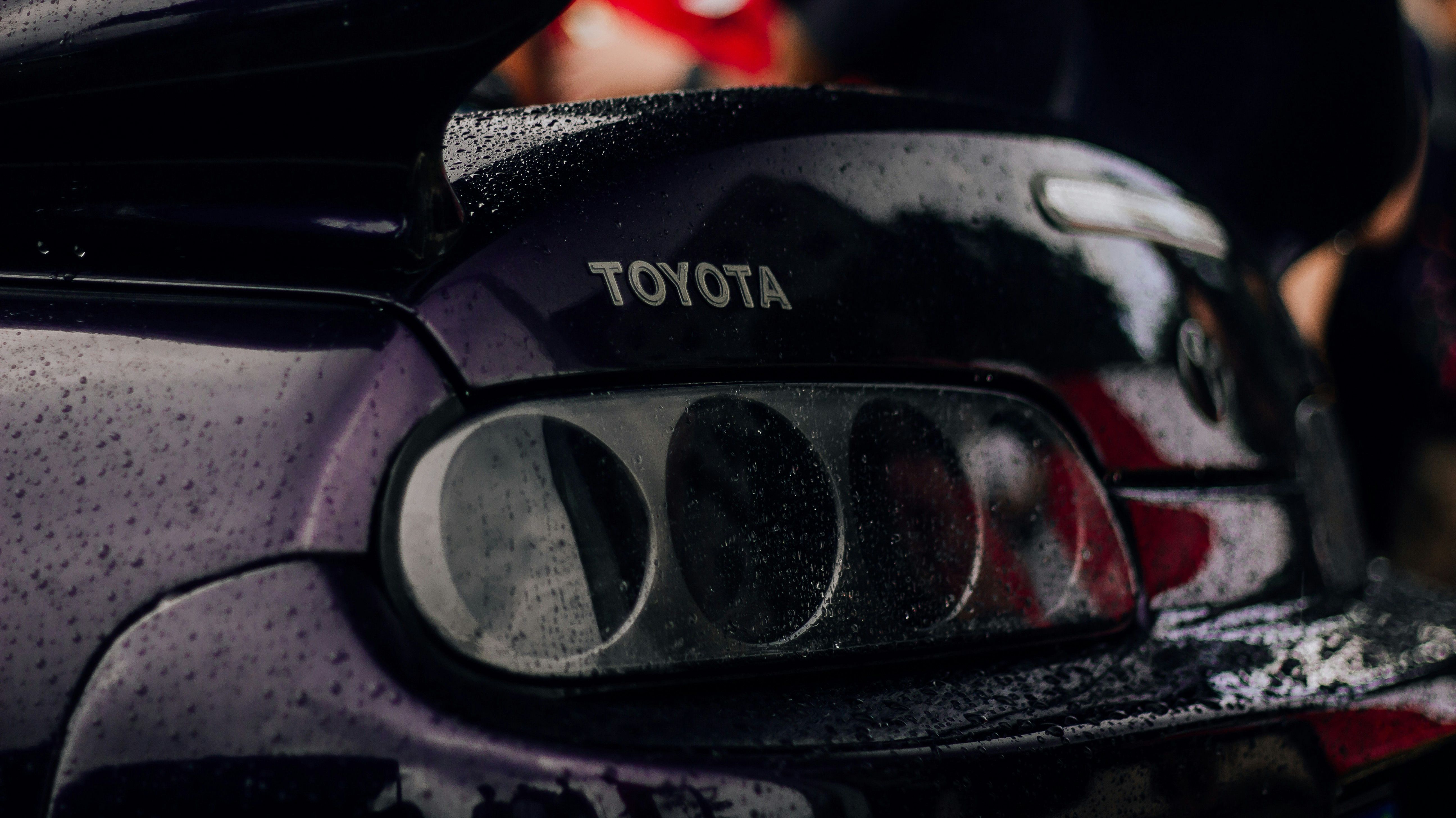 Close-up of a Toyota Supra Mk4 rear, showcasing its iconic taillights and spoiler in a moody, rain-soaked setting. Classic JDM vibes with a focus on the legendary Supra's aggressive design.